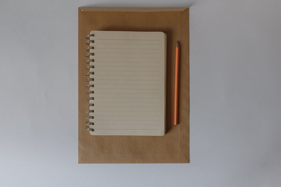 Top-down view of a lined notebook and pencil on an envelope, showcasing minimal design.